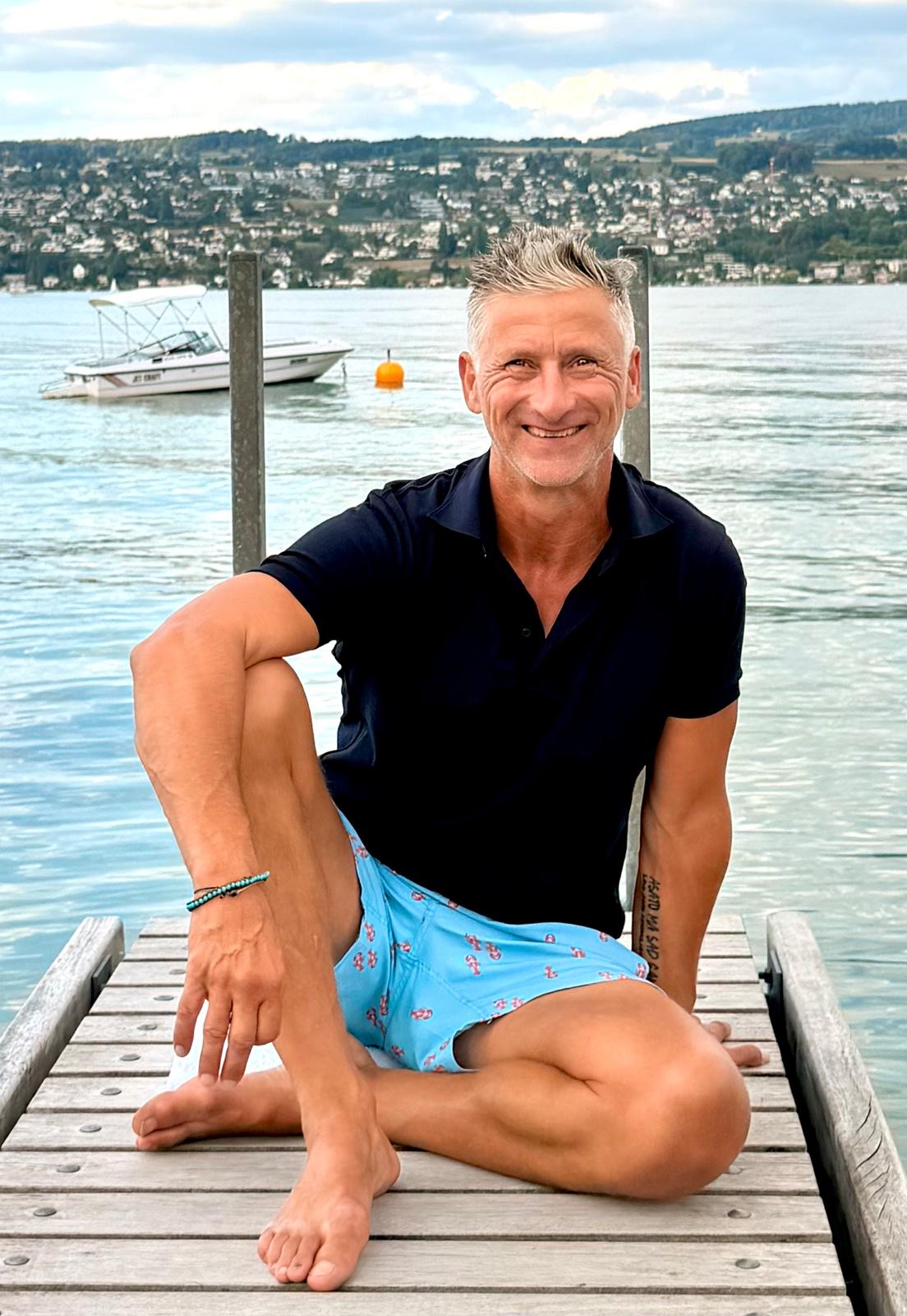 Hardy Krüger sitzt lächelnd an einem See
